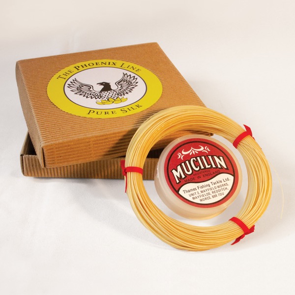 Product photograph of fishing line in straw colour with packaging and a tin of Red Mucilin.